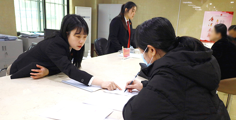 訴訟服務(wù)中心窗口工作人員正在指導(dǎo)前來(lái)立案的王女士填寫要素式起訴狀